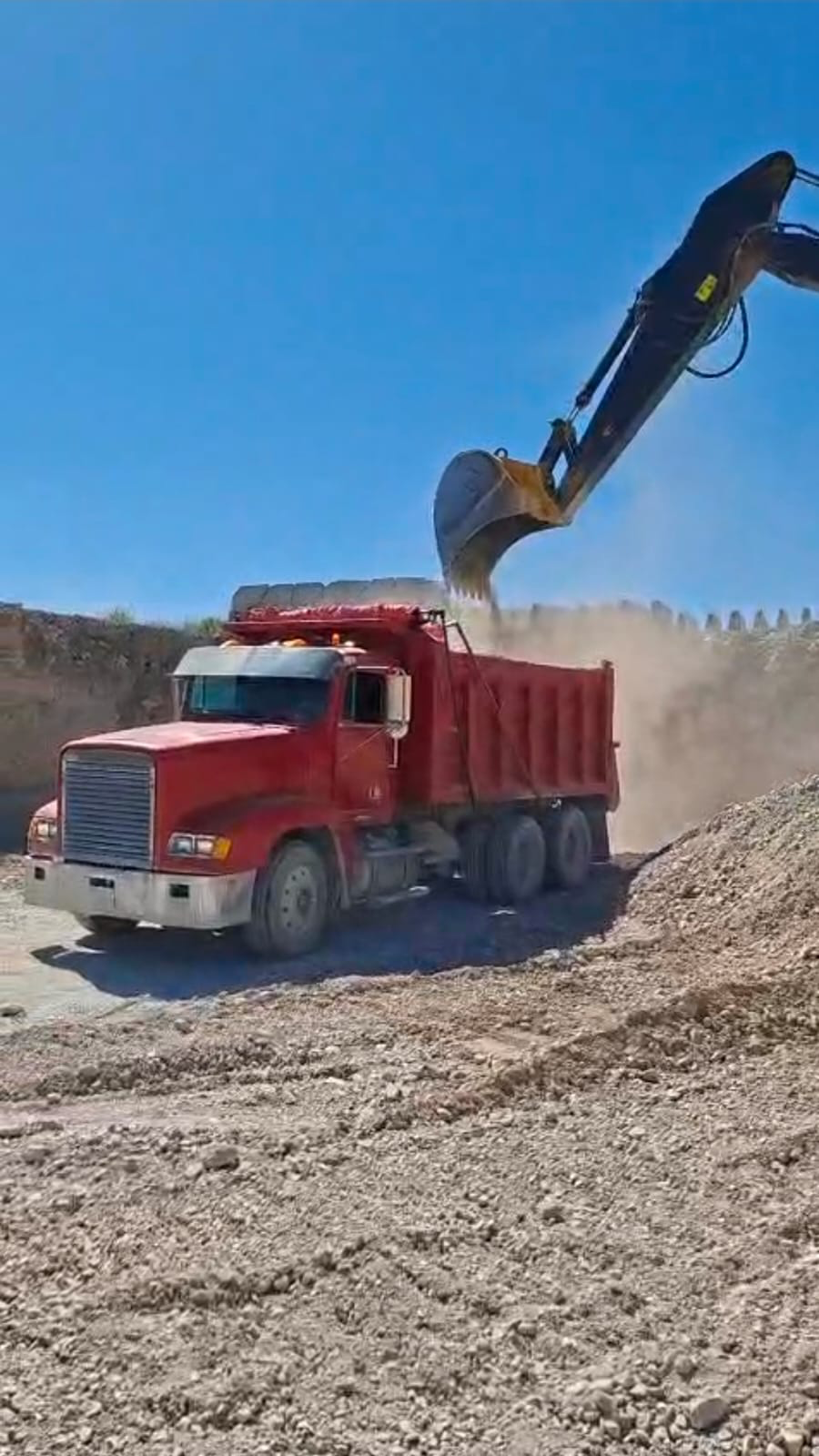 Carga de camión con excavadora en el frente de trabajo.